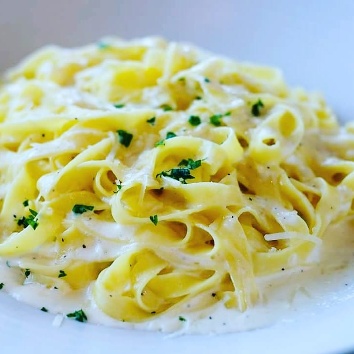 A plate of pasta with cream sauce and parsley.