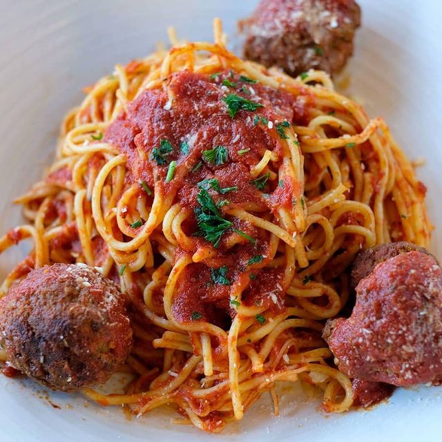 A bowl of spaghetti with meatballs and sauce.