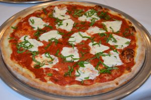 A pizza on a silver plate.