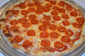 A pepperoni pizza on a silver plate.