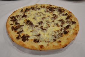 A pizza with cheese and meat on a plate.