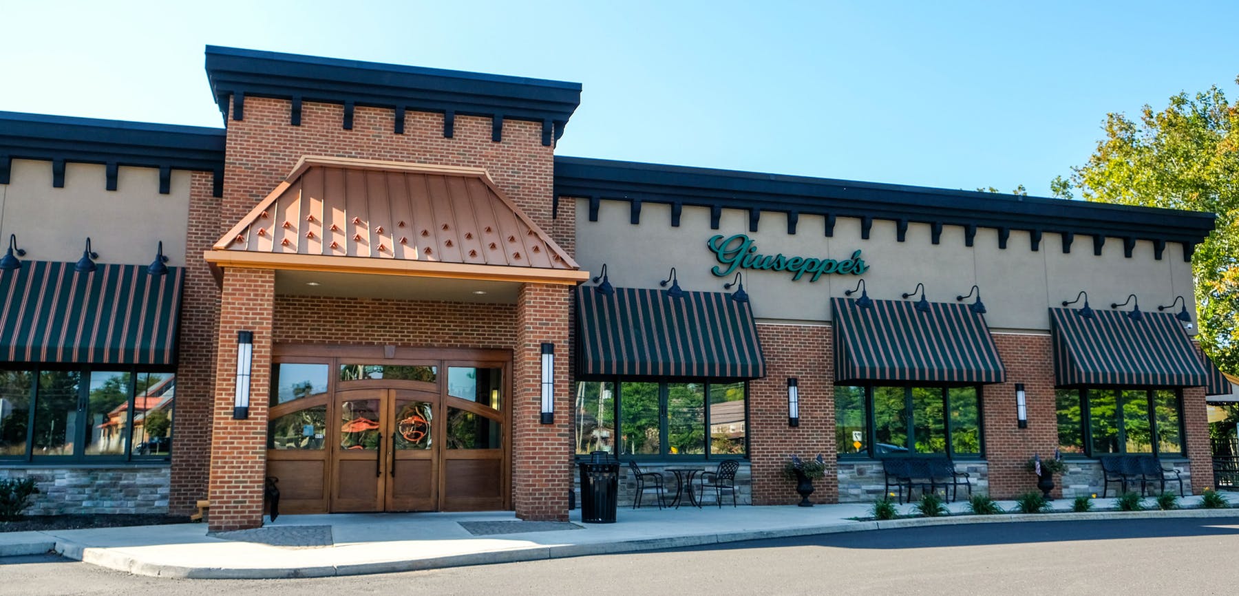 The exterior of a restaurant with a brown awning.
