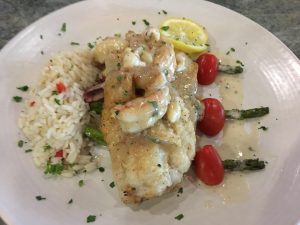 A plate with shrimp, rice and tomatoes.