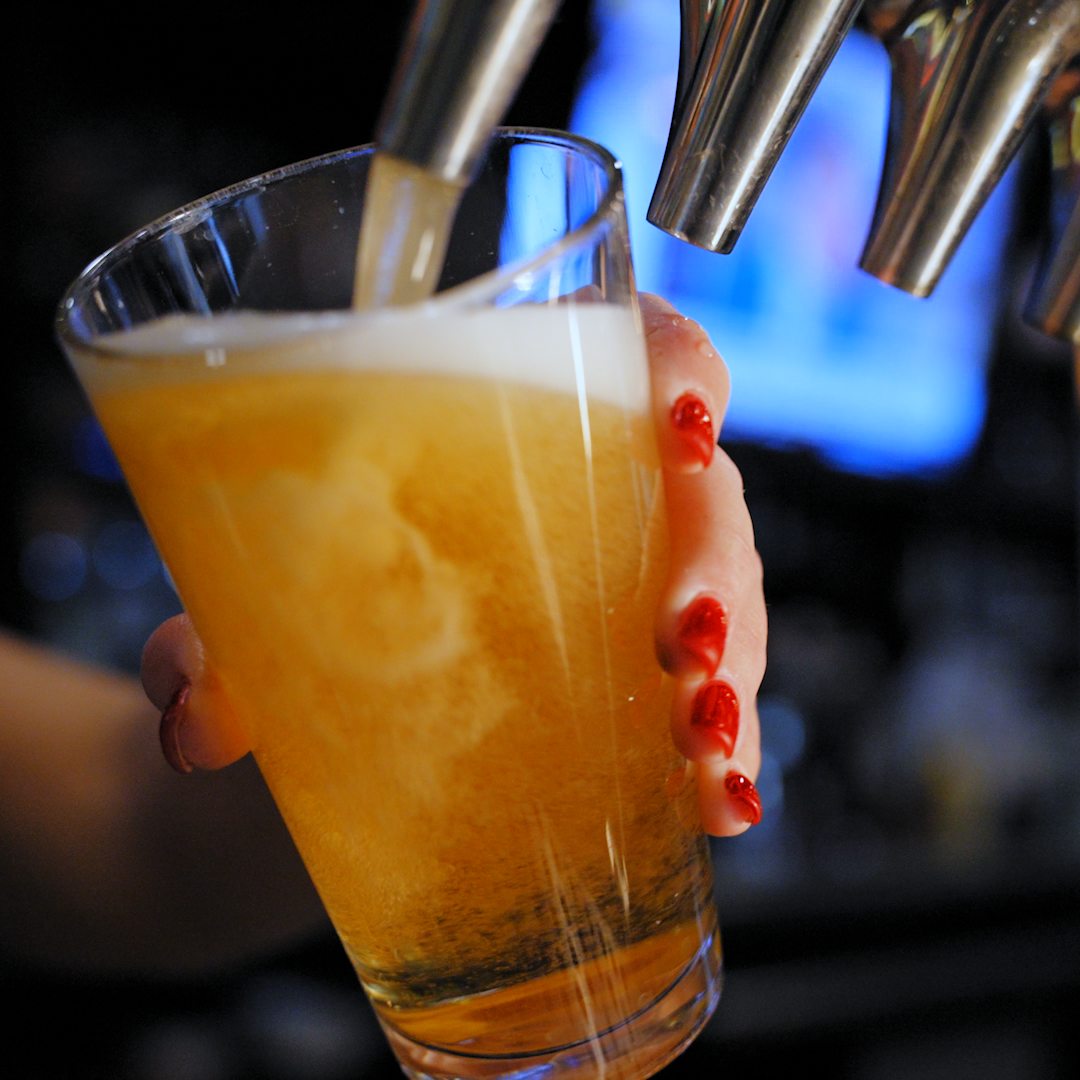 A bartender pouring a beer into a glass.
