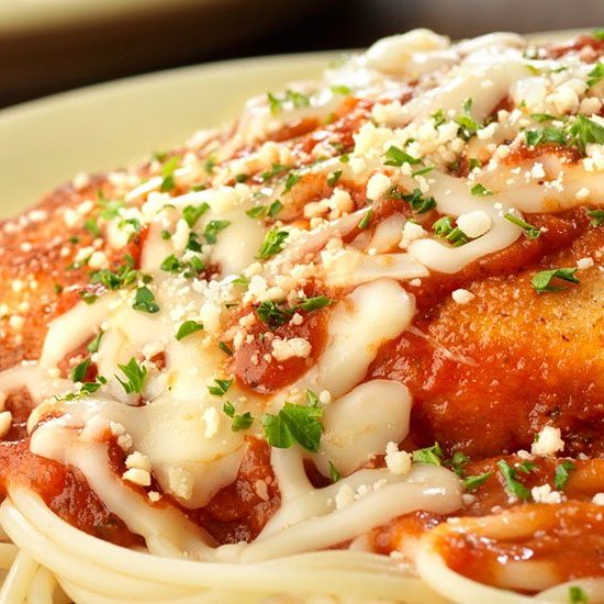 A plate of spaghetti with chicken and sauce.