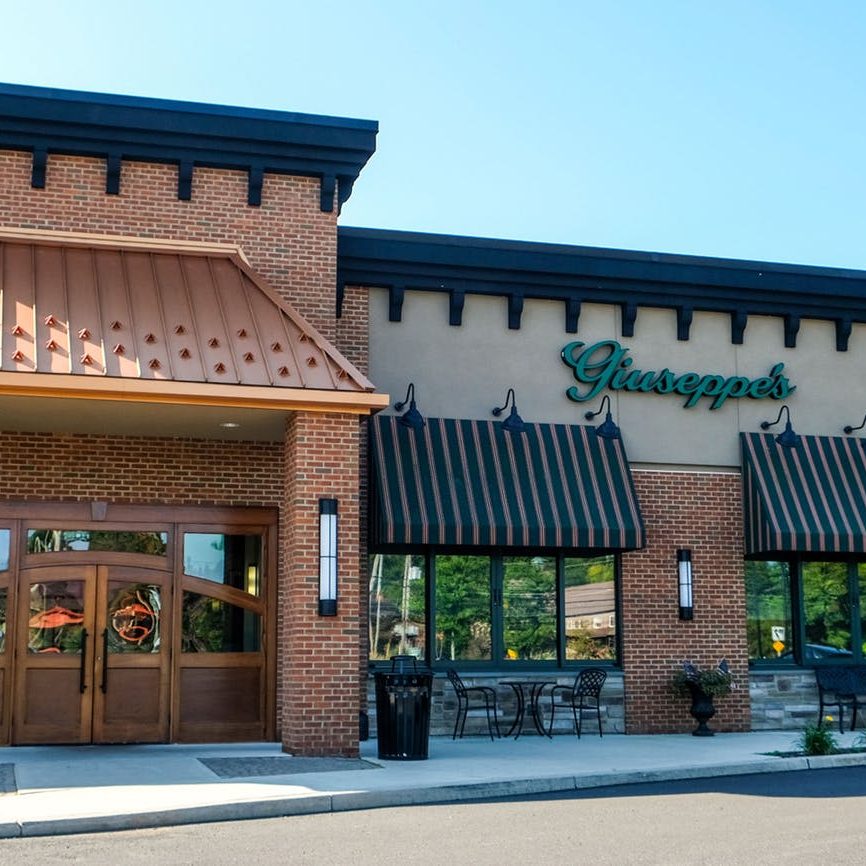 The exterior of a restaurant with a brown awning.