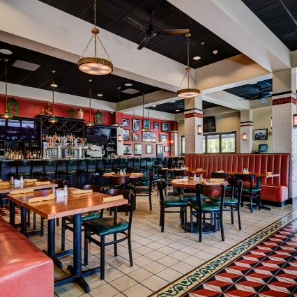 The interior of a restaurant with red booths and tiled floors.