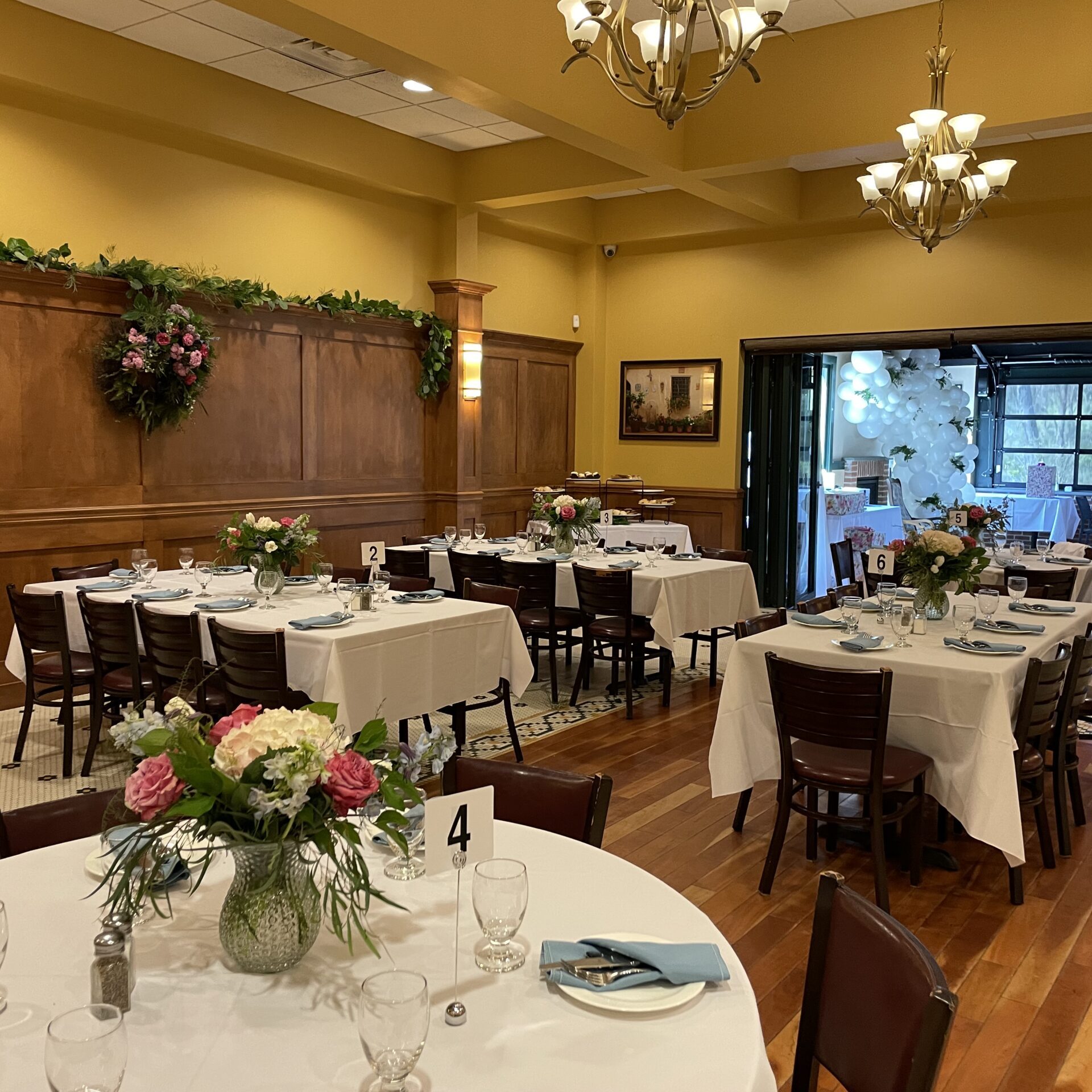 A dining room with tables and chairs set up for a wedding.